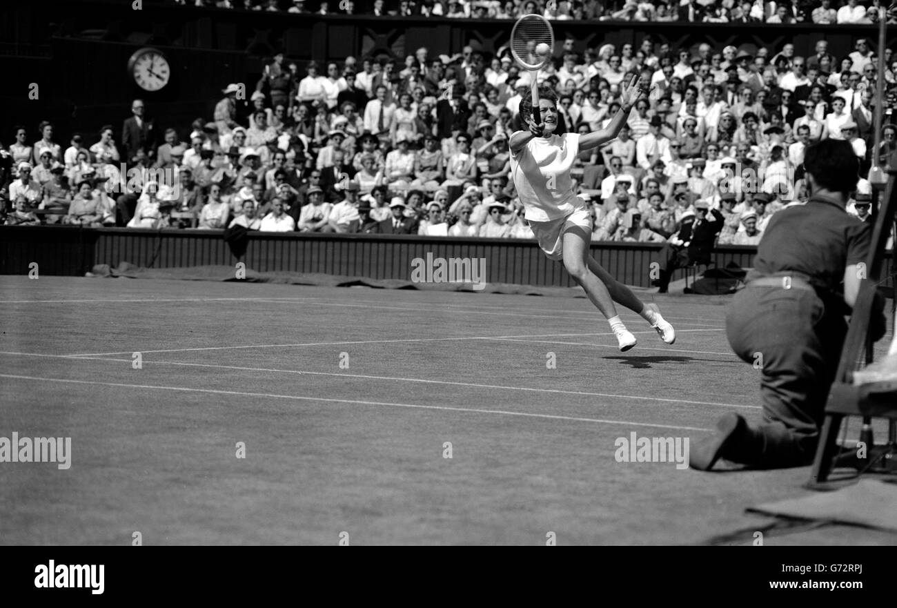 Angela Buxton se moque de ses dents en jouant aux fléchettes à travers le court central pour écraser le ballon à Mme S. le Besnarais dans leur match lors de la première partie des singles féminins des championnats de tennis de Wimbledon. Banque D'Images