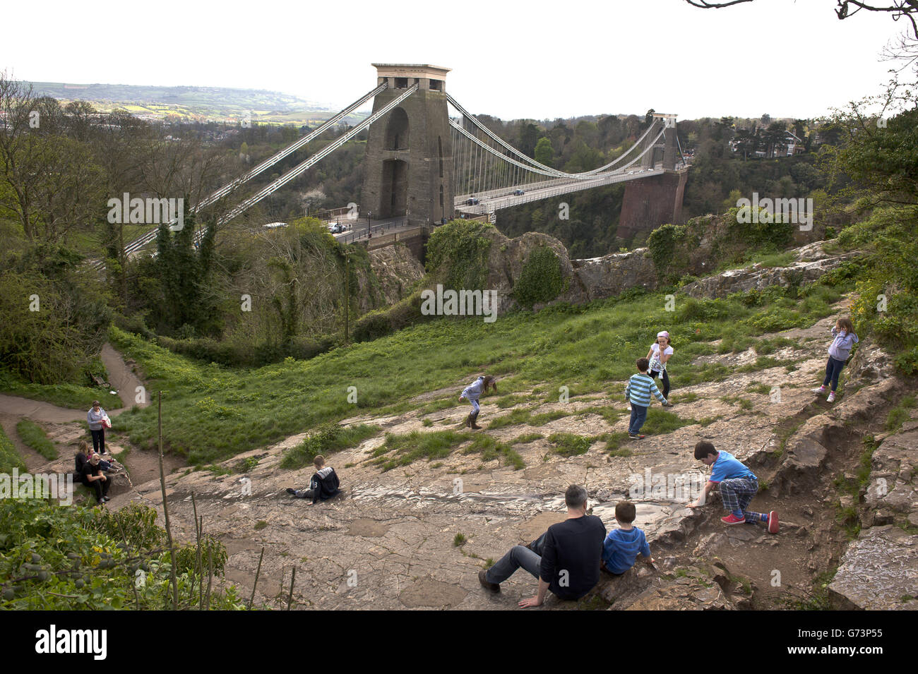 Les enfants glissent sur un toboggan naturel près du pont suspendu Clifton, conçu par Isambard Kingdom Brunel, qui traverse la gorge Avon et la rivière Avon, reliant Clifton à Bristol à Leigh Woods dans le nord du Somerset.Le pont a ouvert en 1864 et est un bâtiment classé de catégorie I, faisant partie de la route B3129 pour laquelle il y a un péage à traverser Banque D'Images