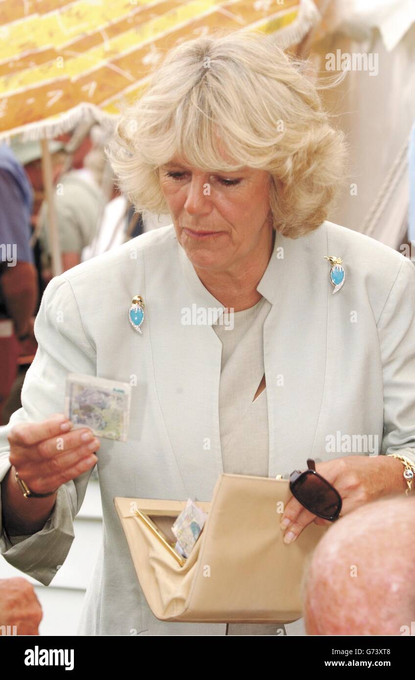La compagne du Prince de Galles, Camilla Parker Bowles, offre une note de 5 dans son sac à main après qu'elle et le prince aient été invités à acheter des billets de tombola lors d'une visite, au spectacle de fleurs de Sandringham sur le domaine royal de Sandringham, Norfolk. Le prince, conformément à la coutume royale, ne transporte pas systématiquement de l'argent. Banque D'Images