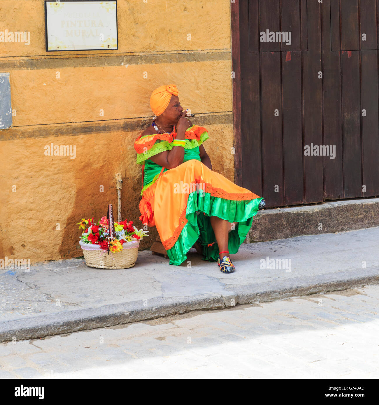 La femme cubaine en robe colorée fumer un cigare à La Habana Vieja, La Vieille Havane, Cuba Banque D'Images