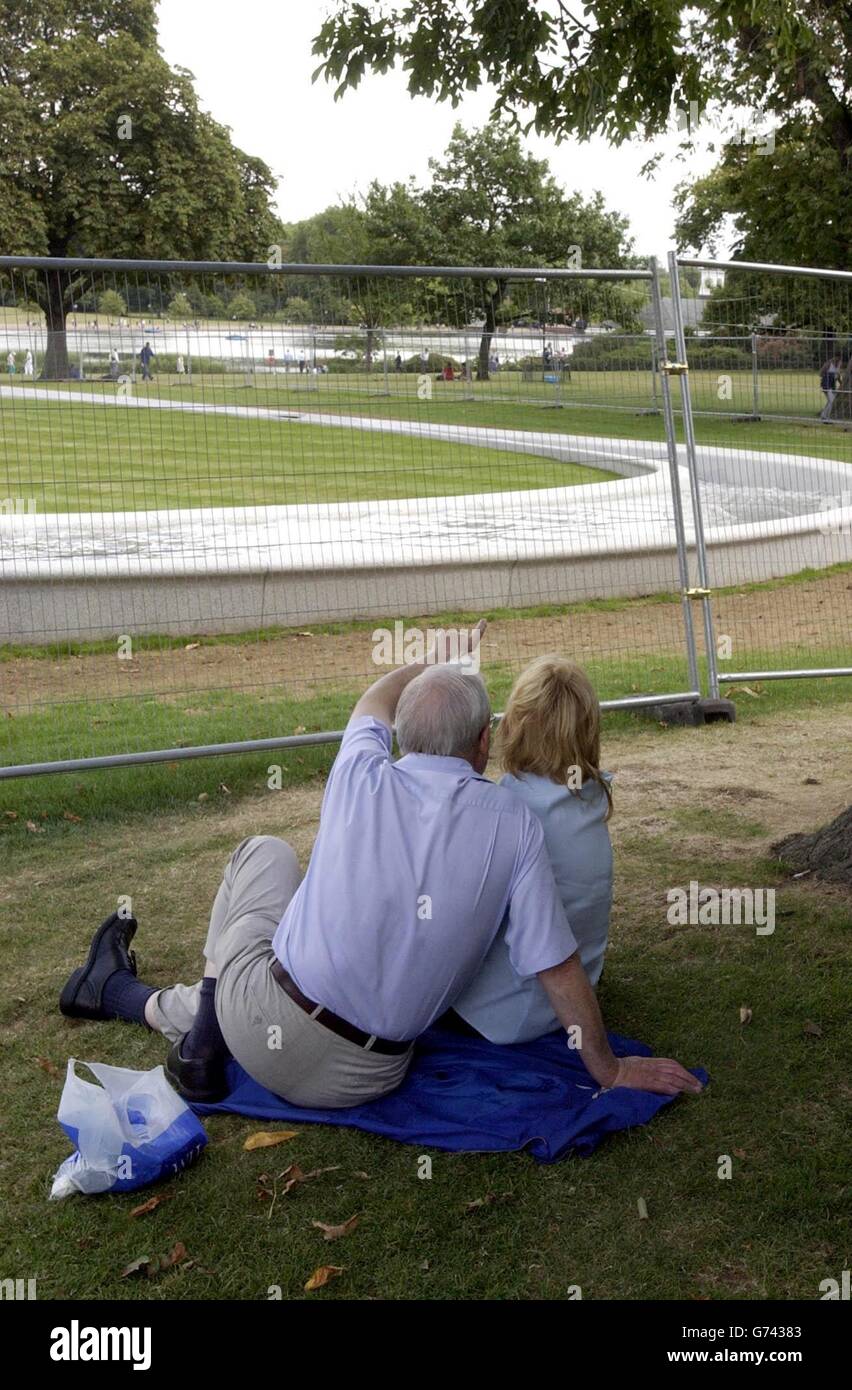 Les voyageurs d'une journée contemplez l'escrime temporaire sur la fontaine Diana Memorial dans Hyde Park à Londres. La fontaine a été fermée en raison de modifications de sécurité et devrait être ouverte au public le 20 août. Banque D'Images