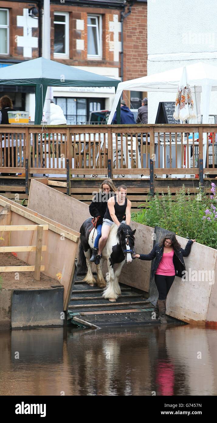 Les membres de la communauté itinérante se préparent à monter à cheval dans la rivière Eden au début de la foire équestre Appleby, le rassemblement annuel des gitans et des voyageurs à Appleby, Cumbria. Banque D'Images