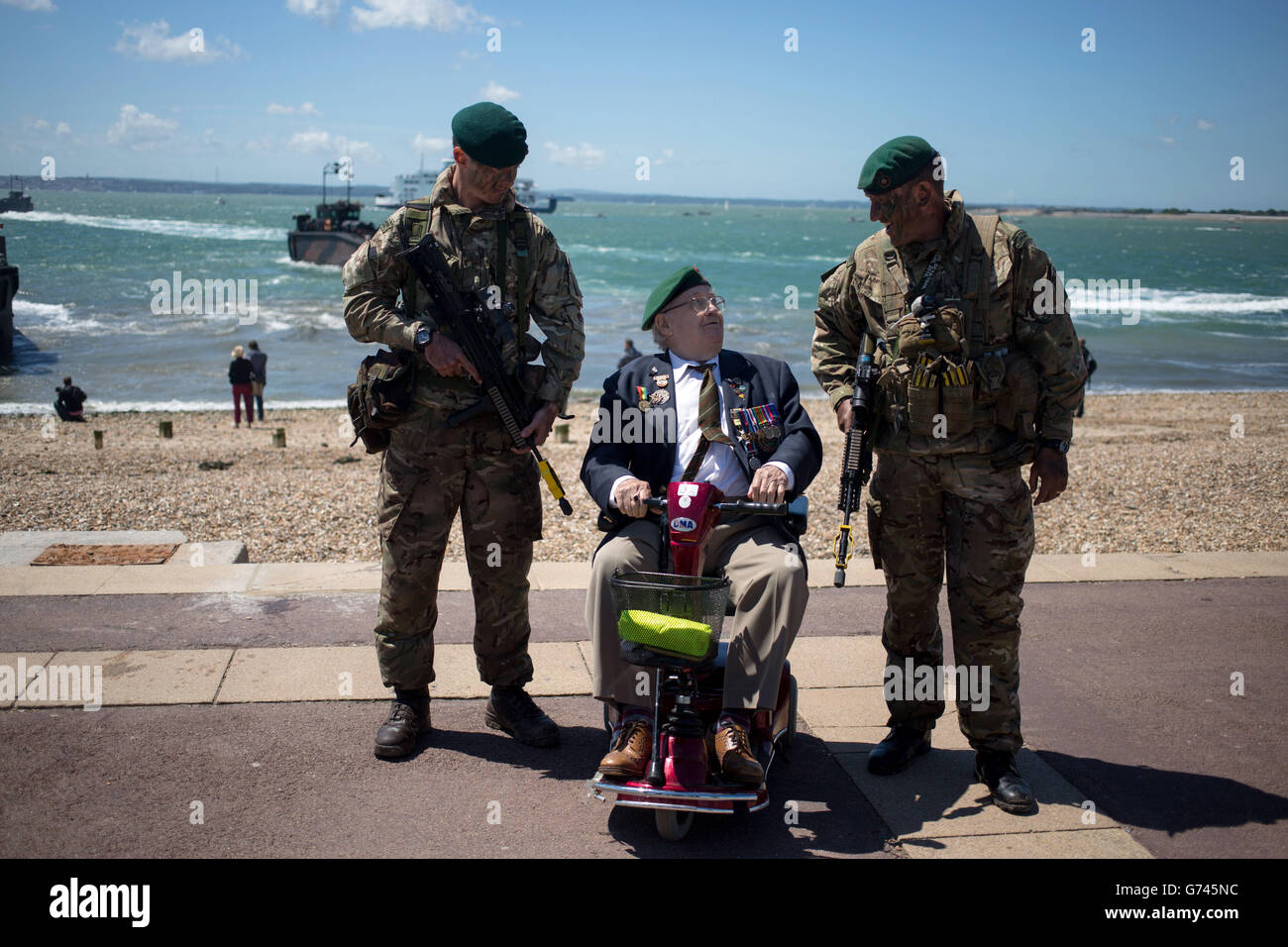 Les commandants maritimes Tom Meehan (à gauche) et Jonathan Bowen discutent avec l'ancien combattant Fred Perkins, 89 ans, après que les Marines et leurs homologues néerlandais aient effectué une invasion de la plage près de Southsea Common dans le Hampshire pour marquer le 70e anniversaire des débarquements du débarquement. Banque D'Images