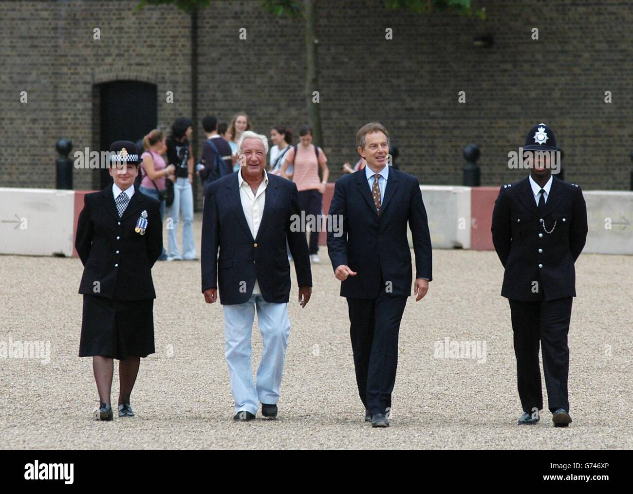Le Premier ministre Tony Blair (deuxième à partir de la droite) marche avec le gendarme de la police métropolitaine Joel Edwards (à droite), Michael Winner (deuxième à partir de la gauche) et Lynn Bialowa (à gauche), gendarme de la police du Grand Manchester (à gauche), sur le chemin d'une visite du monument commémoratif de la police nationale, Whitehall, Londres, le 22 juillet 2004. Le mémorial sera ouvert en octobre 2004 pour commémorer les policiers britanniques qui ont été tués dans l'exercice de leurs fonctions, et est le fruit du fondateur de la police Memorial Trust, Michael Winner. Banque D'Images