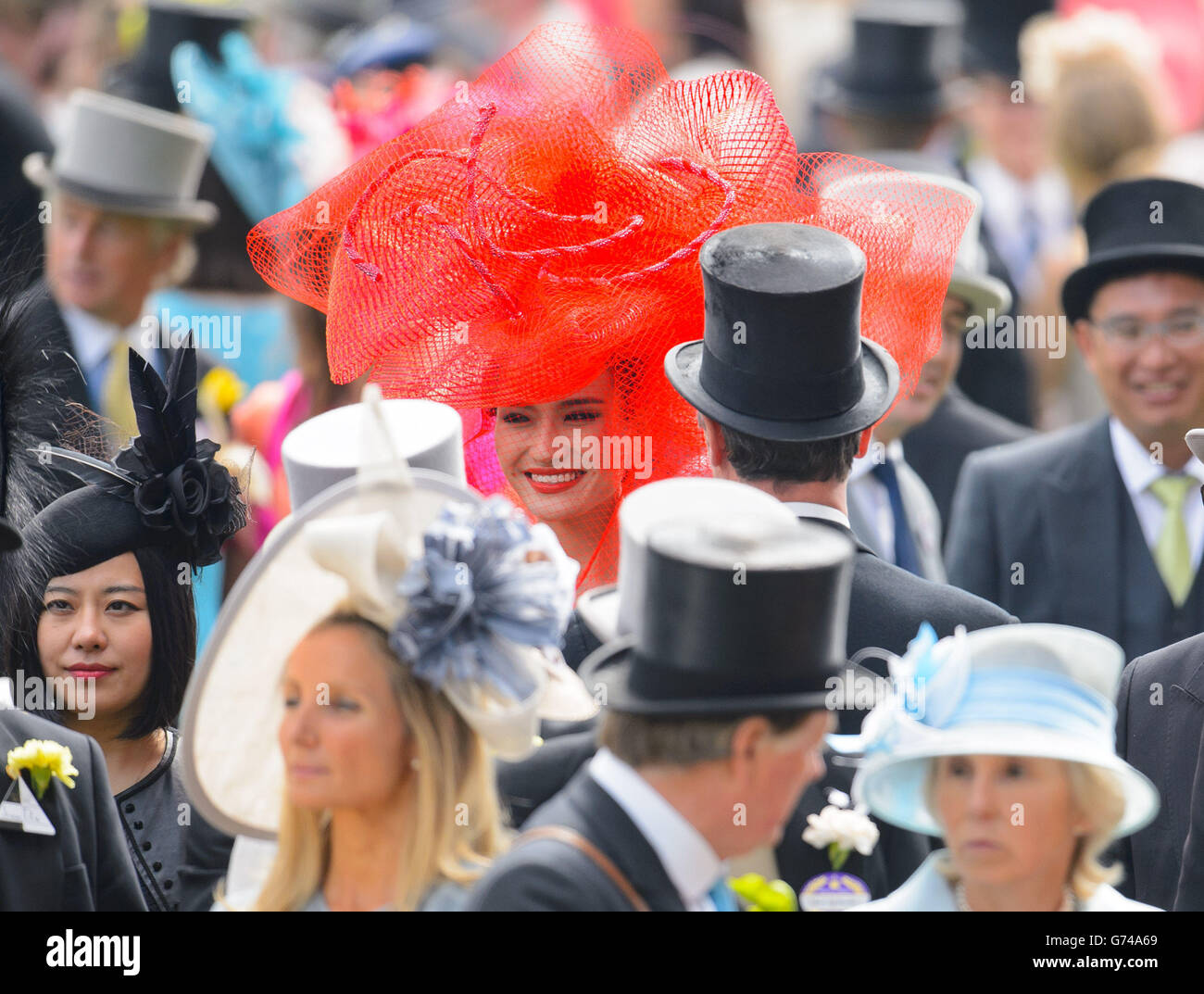 Un coureur dans un grand chapeau rouge dans l'anneau de parade pendant le troisième jour de la réunion royale d'Ascot de 2014 à l'hippodrome d'Ascot, Berkshire. Banque D'Images