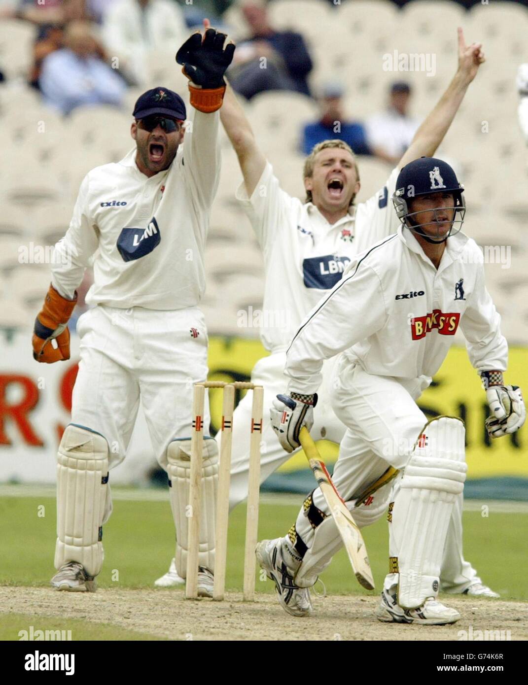 Le gardien de cricket du Lancashire Jamie Haynes et le premier slip Dominic Cork font appel sans succès pour un appel LBW contre le batteur du Warwickshire Brad Hogg lors du match de la division de championnat du comté de Frizzell à Old Trafford. Banque D'Images