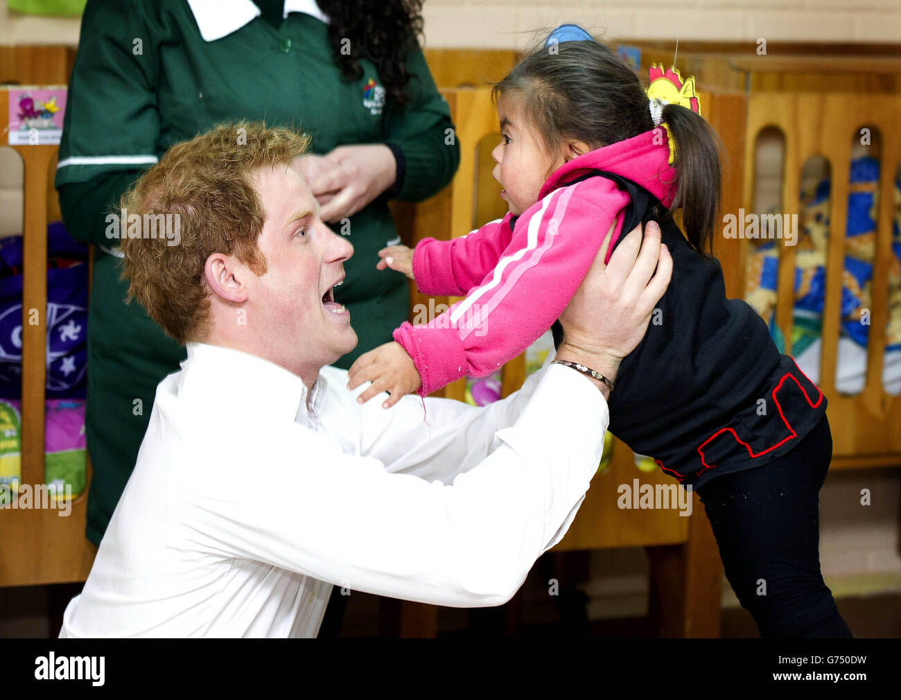 Le Prince Harry ramasse une jeune fille lors d'une visite à un jardin d'enfants pour les enfants autochtones à Santiago, au Chili.APPUYEZ SUR ASSOCIATION photo.Date de la photo: Vendredi 27 juin 2014.Voir l'histoire de l'AP, ROYAL Harry.Le crédit photo doit être lu : Dan Charity/The Sun/PA Wire Banque D'Images