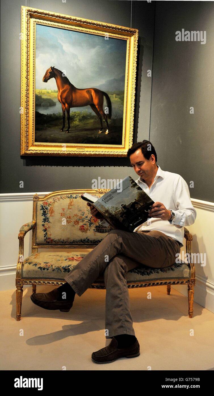 James Harvey, marchand d'arts sportifs britannique, lit un livre sur l'artiste George Stubbs alors qu'il est assis sous « A Bay Colt », vers 1755-59, la première œuvre de l'artiste britannique des animaux,Qu'il a proposé pour &Pound;425,000 au chef-d'œuvre London art and antiques Fair, dans le South Grounds, du Royal Hospital Chelsea, Londres. Banque D'Images