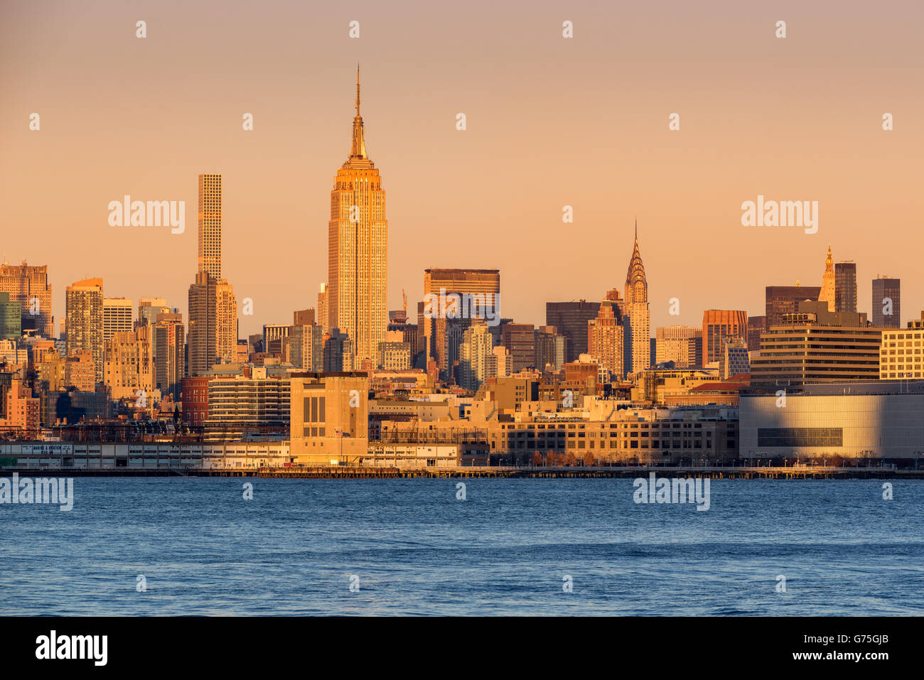 New York City Manhattan gratte-ciel au coucher du soleil de l'autre côté de la rivière Hudson. Au centre, l'Empire State Building. Banque D'Images