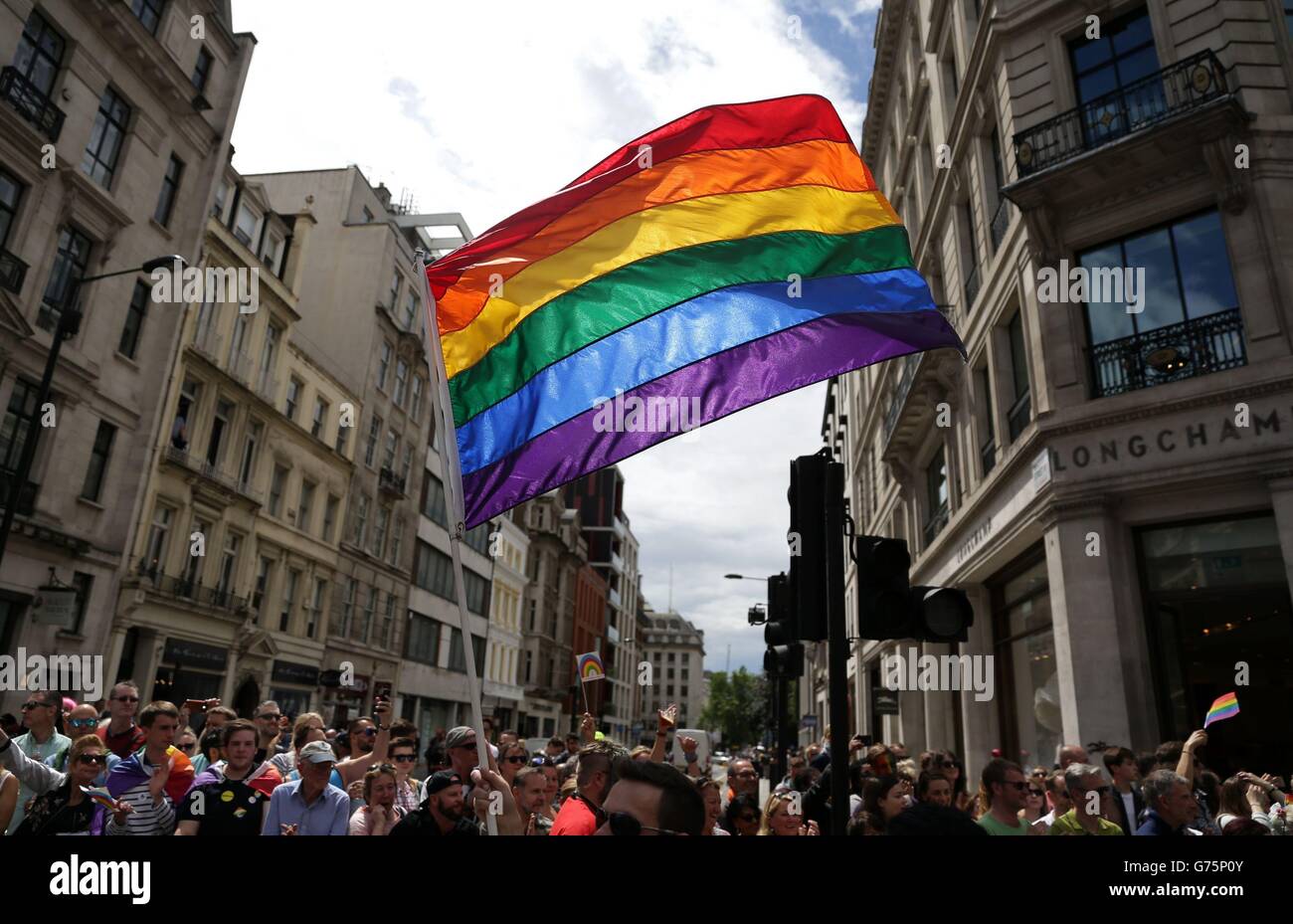 Un drapeau arc-en-ciel est tenue en altitude comme la fierté de Londres parade fait son chemin à travers les rues du centre de Londres. Banque D'Images