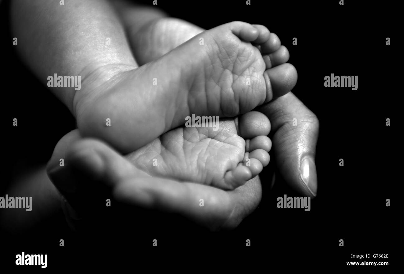 Une mère berce les pieds de son nouveau-né dans sa main Banque D'Images