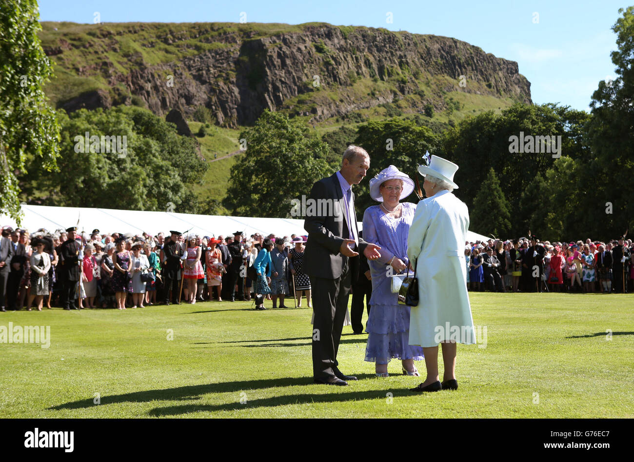 La reine Elizabeth II s'adresse aux clients lorsqu'elle organise une fête dans le jardin avec Arthur Seat en arrière-plan à la maison du palais de Holyrood à Édimbourg. Banque D'Images