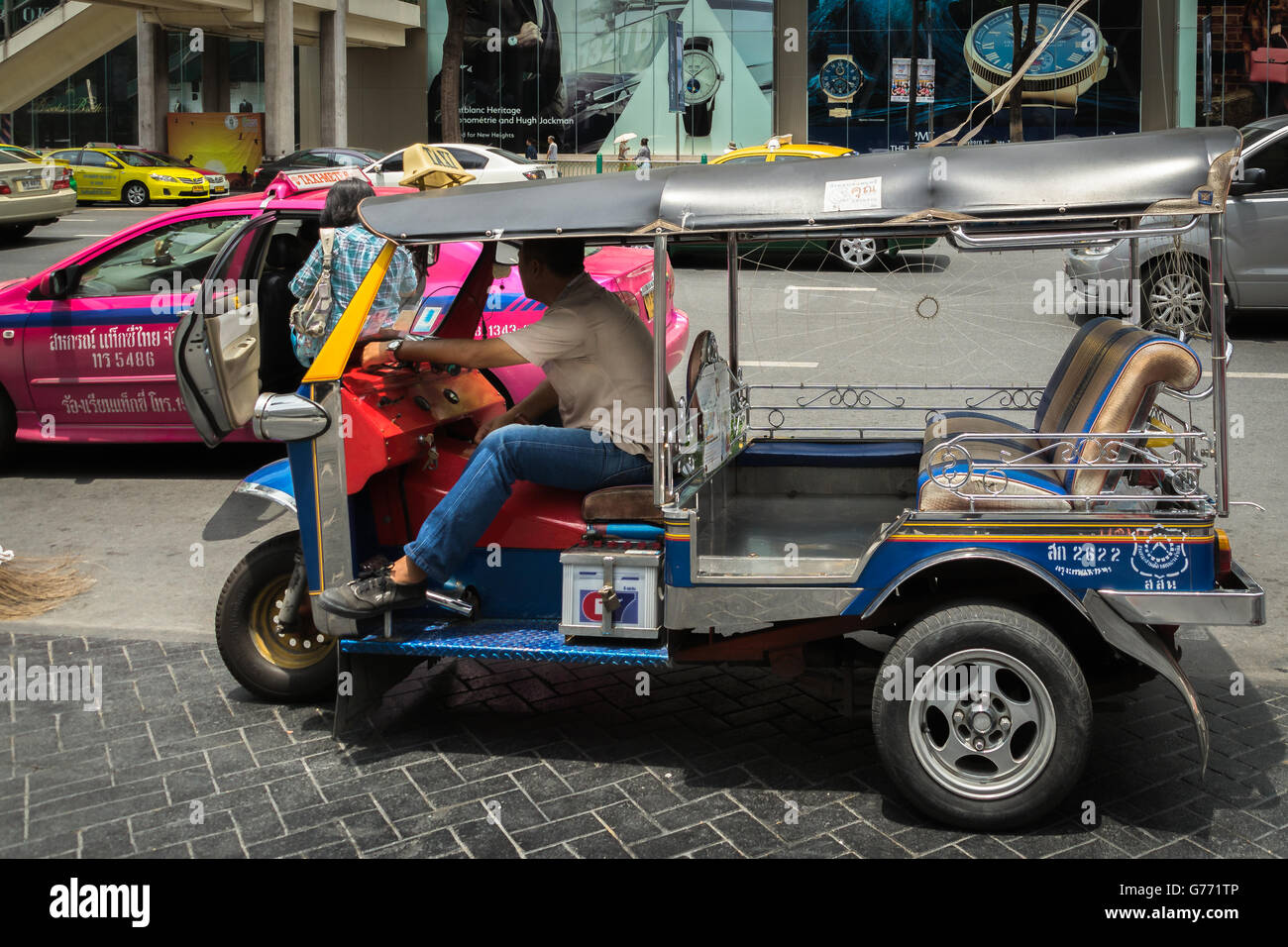 Un chauffeur de tuk tuk et un taxi rose dans le quartier commercial de Bangkok, en Thaïlande Banque D'Images