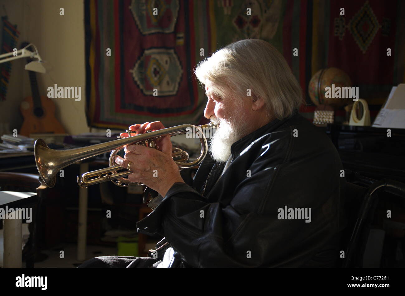 Éclairage latéral puissant capture musicien Robert Wyatt soufflant sa trompette dans son studio de Lincolnshire. Banque D'Images