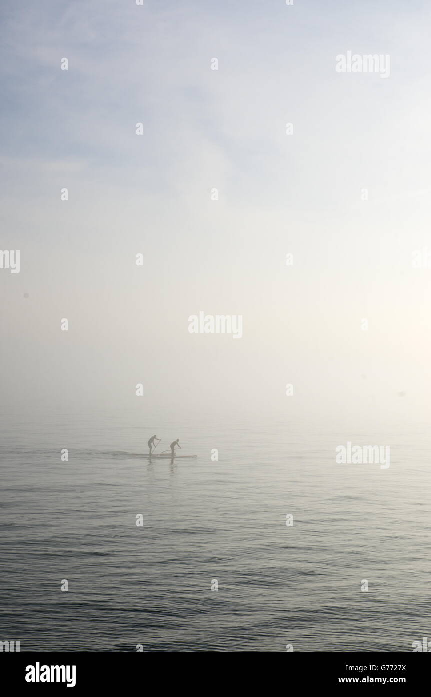 Deux Paddleboarders font leur chemin à travers la brume à Hove. Banque D'Images