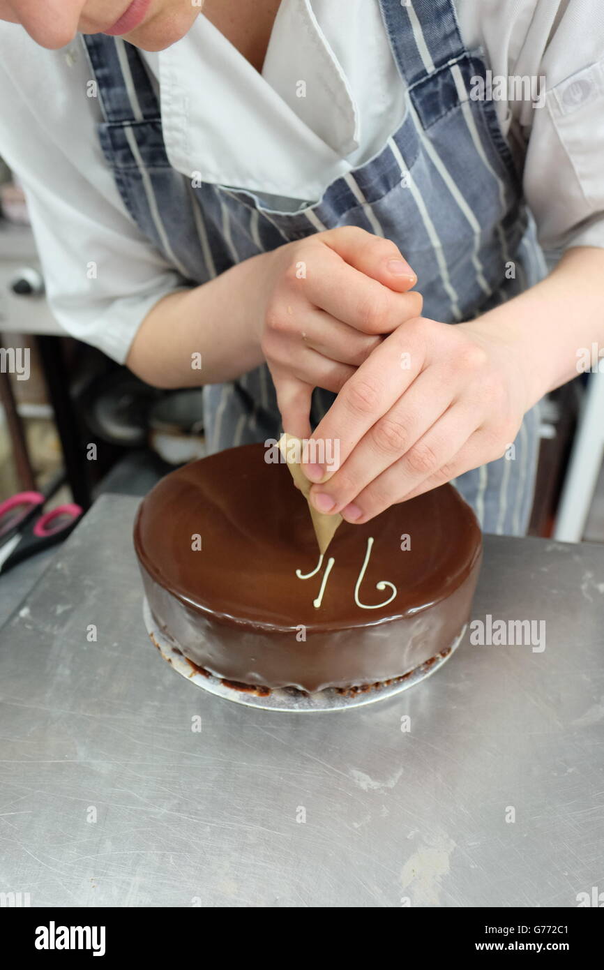 Un Jeune Chef Patissier Savamment Ecrit Sur Une Ganache Au Chocolat Gateau D Anniversaire Photo Stock Alamy