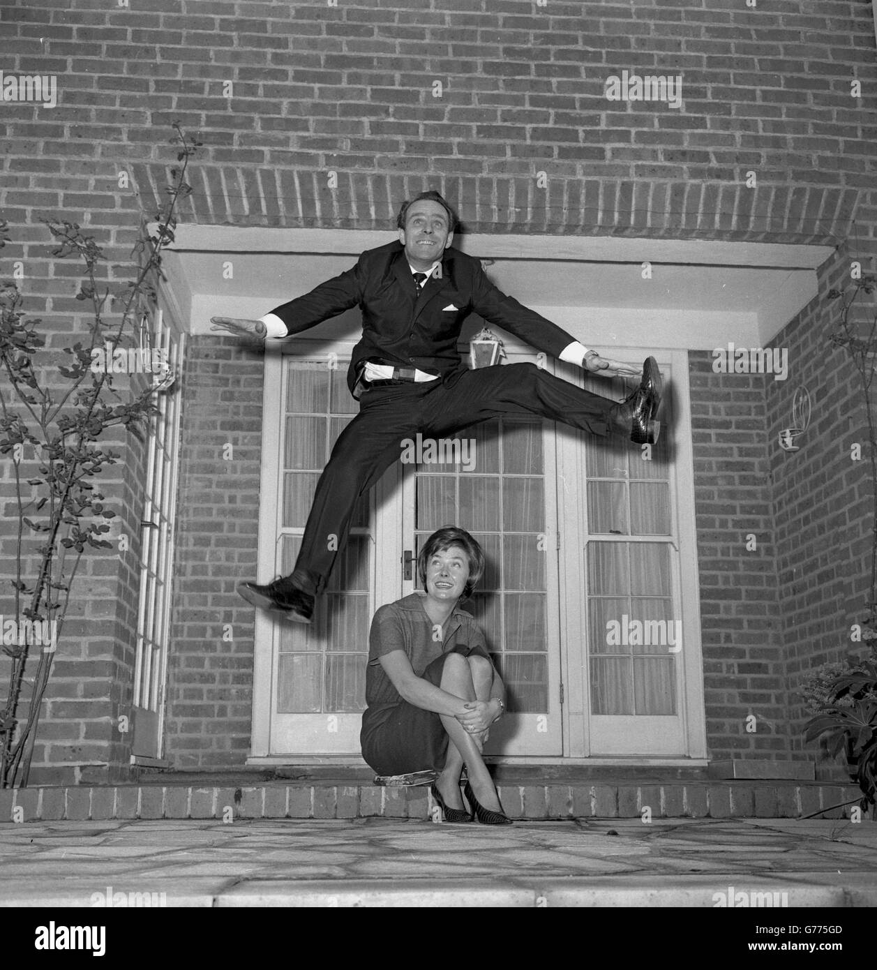 Dickie Henderson, la star de la télévision populaire, fait un bond en avant pour la joie face à Dixie, son élégante femme née au Texas, chez elle à Kensington, à Londres. Dickie est surjoyeuse lorsqu'il célèbre son 37e anniversaire. Il prépare actuellement une nouvelle série télévisée, 'The Dickie Hendrson Show', qui sera vue sur AR-TV pendant six mois, à partir du lundi 13 novembre. Banque D'Images