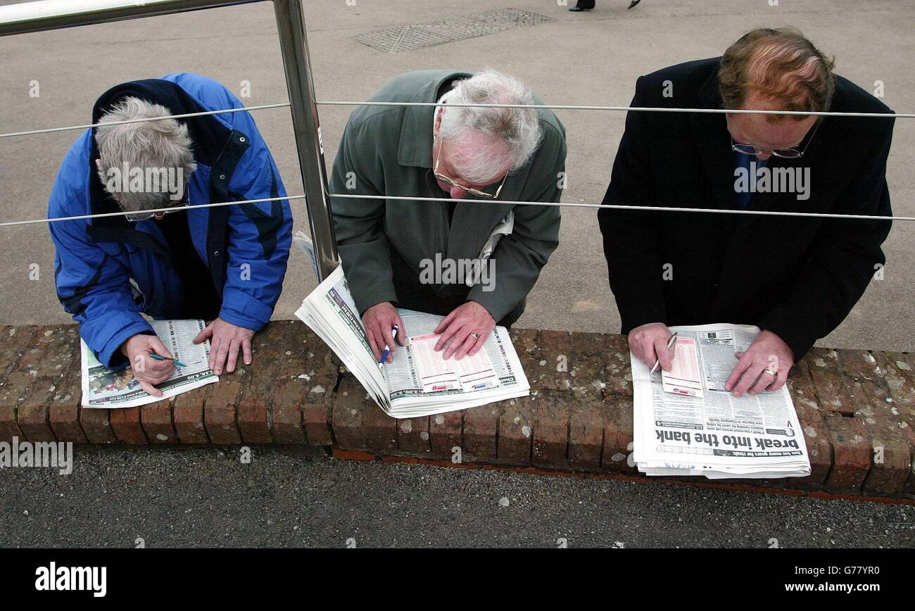 Les punters vérifient le formulaire et remplissent leurs bordereaux de mise avant les courses des jours d'ouverture du Cheltenham Festival, Cheltenham. Banque D'Images