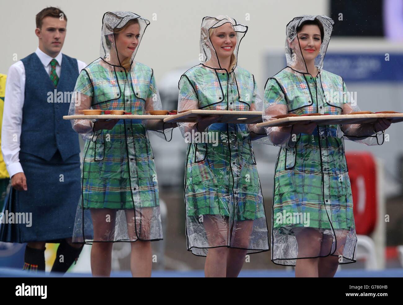 Cérémonie les filles portent les médailles portant des vestes imperméables sous la forte pluie lors de la cérémonie pour le relais d'équipe mixte de Triathlon au Strathclyde Country Park lors des Jeux du Commonwealth 2014 près de Glasgow. Banque D'Images