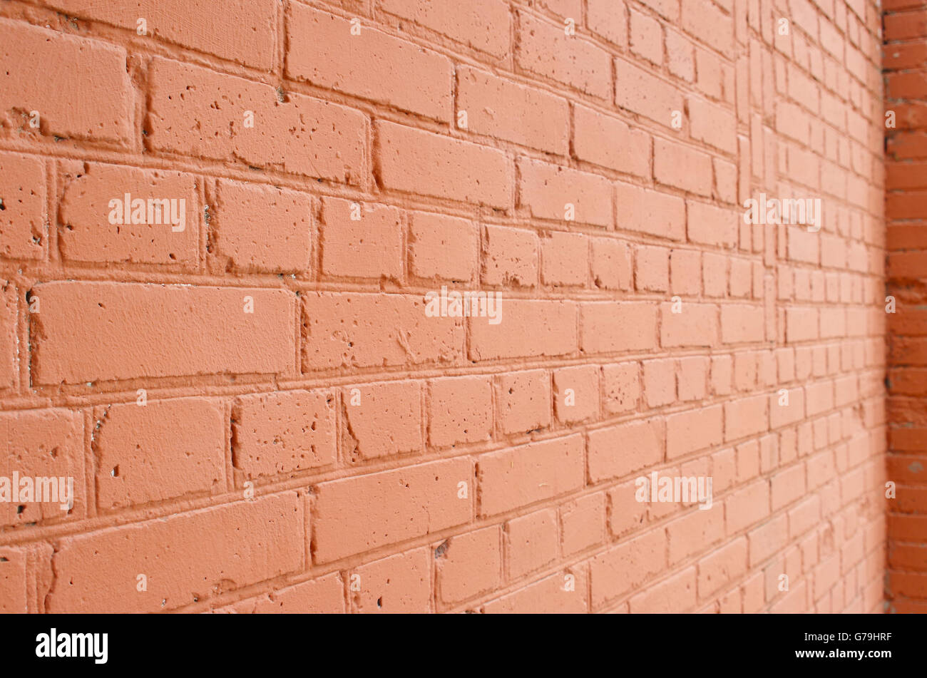 Vue de l'angle d'un mur de briques avec une couche de peinture rouge floue avec plan à long terme pour l'utiliser comme arrière-plan. Banque D'Images
