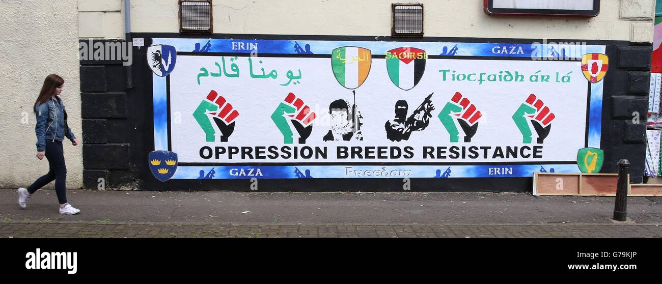 Une jeune femme passe devant une fresque pro-palestinienne sur la Falls Road à Belfast tandis que les groupes loyalistes et républicains prennent des positions rivales pour soutenir Israël et la Palestine pendant la flambée actuelle du conflit. Banque D'Images