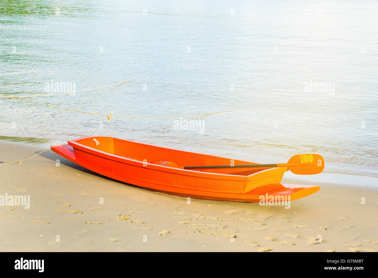 Bateau orange sur la plage de sable avec la mer bleu et le fond de ciel dans la lumière du soir Banque D'Images