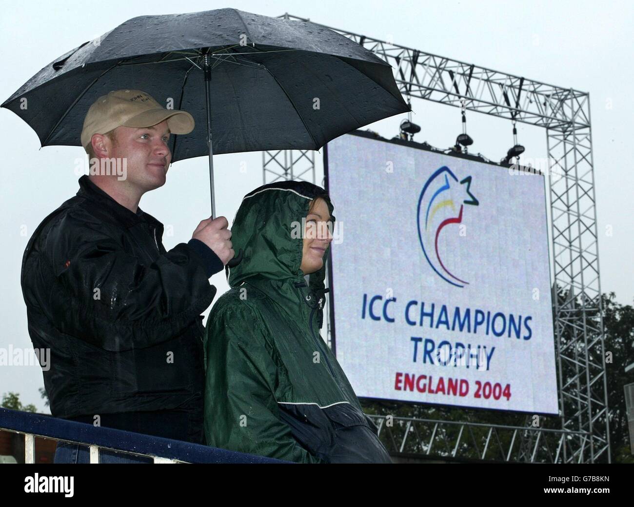 Les fans de cricket se réfugient sous un parapluie tandis que les arrêts de pluie jouent à Edgbaston avec l'Angleterre en raison de jouer au Zimbabwe pendant le premier match du Trophée des champions de l'ICC, un jour international à Edgbaston, Birmingham. Banque D'Images