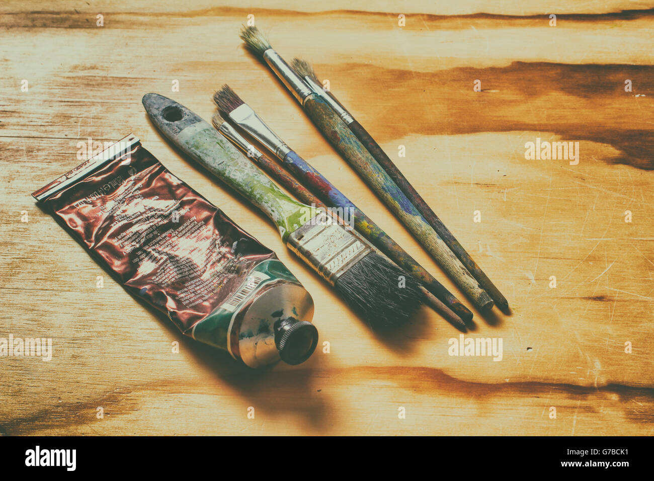 Photographie d'un tube de peinture et quelques pinceaux art sur une table en bois Banque D'Images