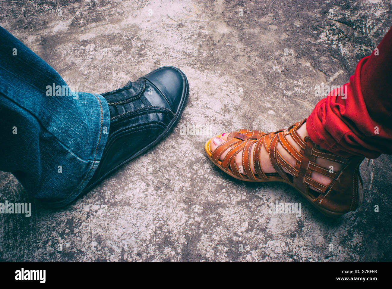 Photographie d'un mans pied portant une chaussure de tennis et d'un pied de femme portant une sandale Banque D'Images