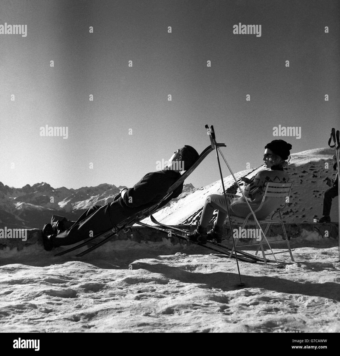 Ce skieur trouve ses skis et ses bâtons faire une chaise de pont temporaire pendant qu'il se détend au soleil. Banque D'Images