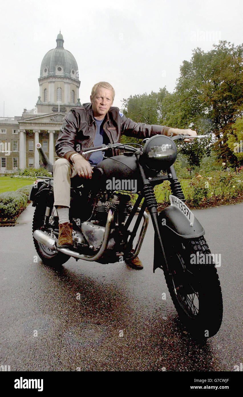 Steve McQueen lookosoainsi Mark Myers pose avec une réplique de la moto  1961 Triumph 650 cc utilisée dans le film 'The Great Escape', à l'extérieur  du Musée impérial de la guerre, dans