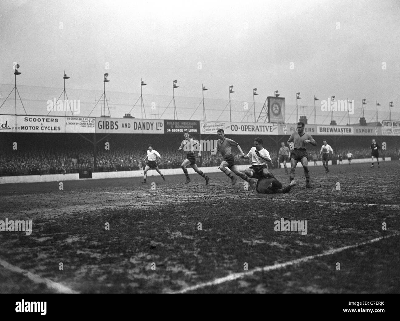 Geoffrey Sidebottom, gardien de but de Wolverhampton Wanderers, plonge au pied de Ken Hawkes de Luton Town, sous la surveillance de John Harris et Eddie Stuart de Wolverhampton Wanderers. Banque D'Images