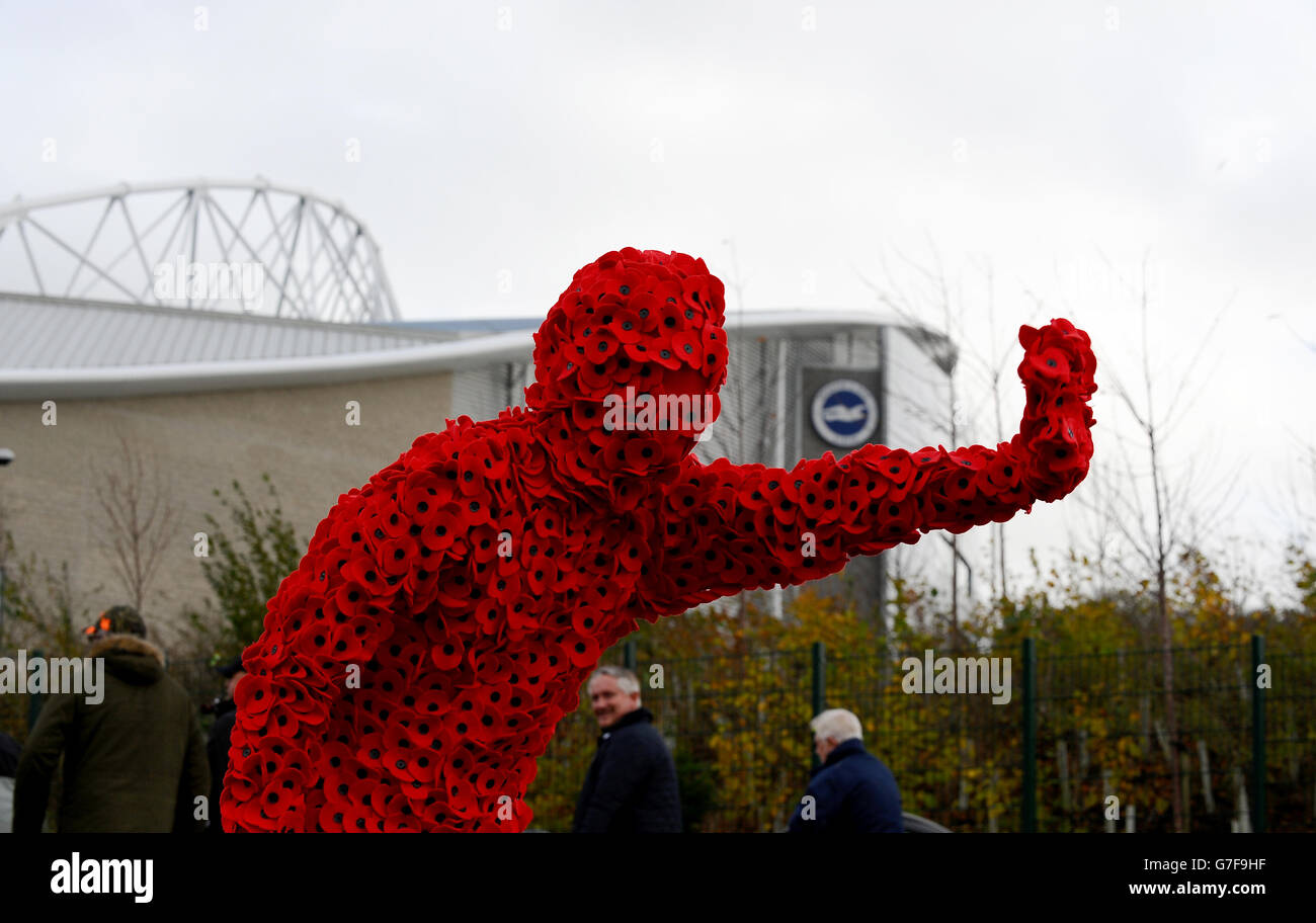 Un homme vêtu d'un costume plein corps de coquelicot se rassemble pour l'attrait du coquelicot avant le match du championnat Sky Bet au stade AMEX de Brighton. Banque D'Images