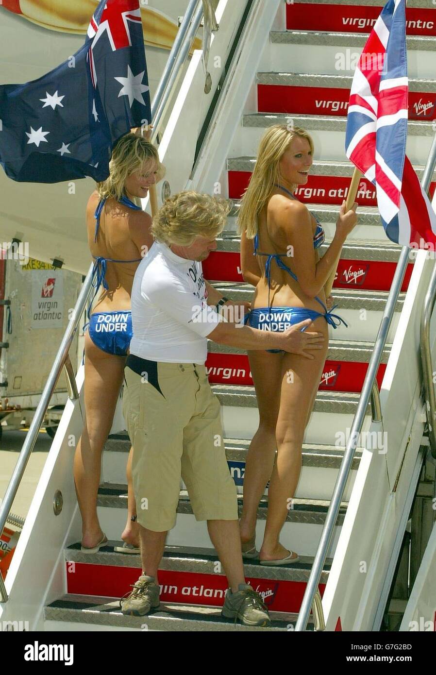 Sir Richard Branson se tient sur les pas de son nouvel avion « inspectant » deux modèles portant des drapeaux du Royaume-Uni et de l'Australie, après qu'il a atterri à l'aéroport international de Sydney pour marquer le lancement du vol inaugural de Virgin Atlantic à destination de l'Australie depuis le Royaume-Uni via Hong Kong. Banque D'Images