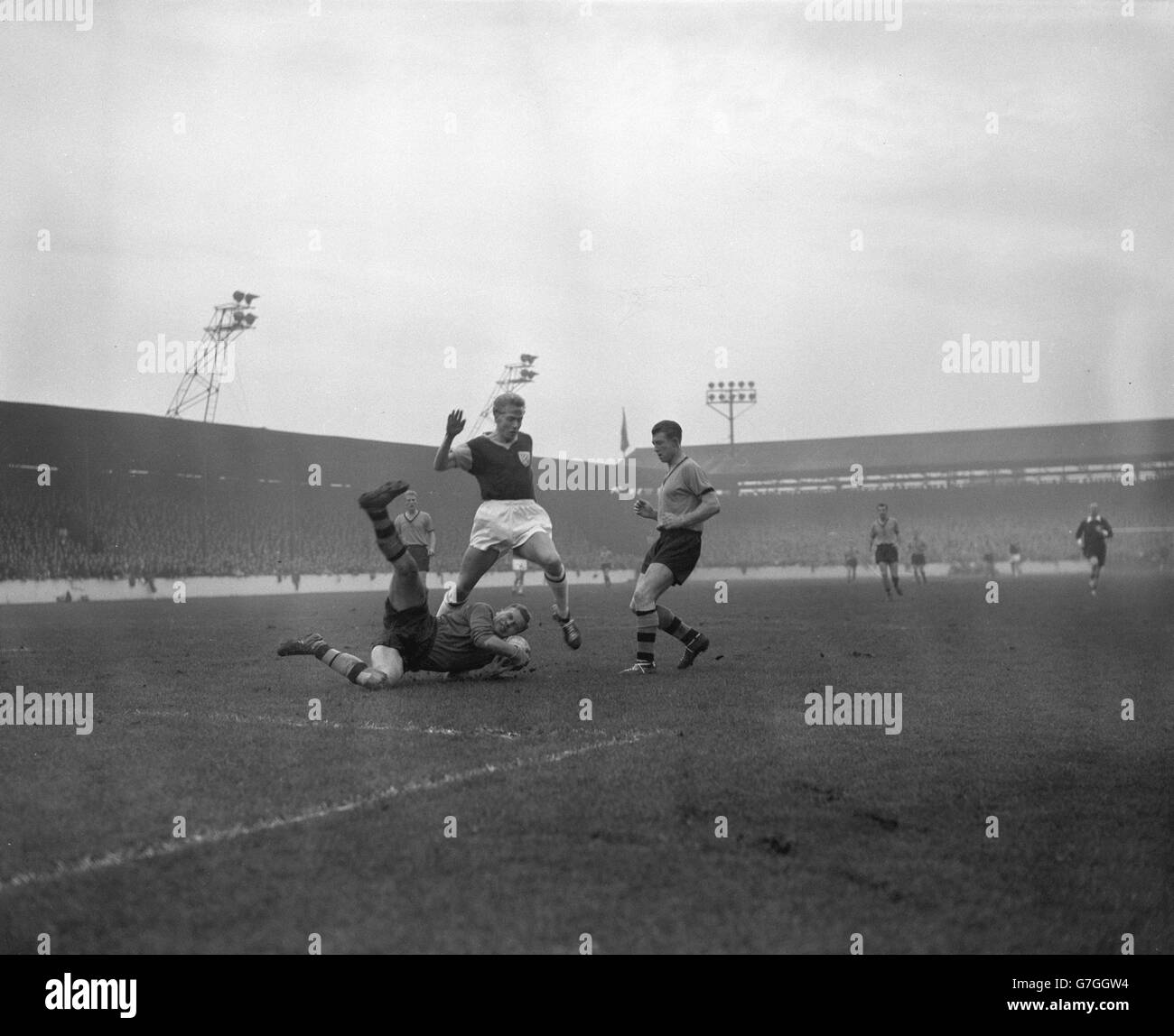 Le gardien de but de Wolverhampton Wanderers Malcolm Finlayson prend le ballon pendant qu'il fait une plongée spectaculaire aux pieds de West Ham United centre-avant Harry Obeney pendant le match de première division à Upton Park.Sur la droite se trouve West Ham juste en arrière George Showell. Banque D'Images