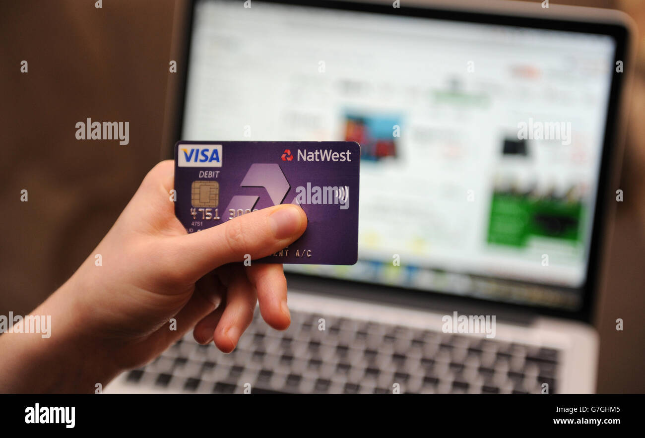 NOTE AUX ÉDITEURS : détails de la carte de débit masqués dans Photoshop. Une femme utilise un ordinateur portable pour naviguer sur le site Web Amazon Banque D'Images