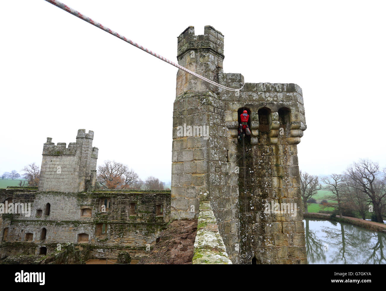 Sam Milford un technicien d'accès à la corde ou un « marcheur mural » de la société Highline Access Ltd, spécialisée de Bristol, enlève les mauvaises herbes à la main des murs du château de Bodiam près de Robertsbridge, East Sussex. Banque D'Images