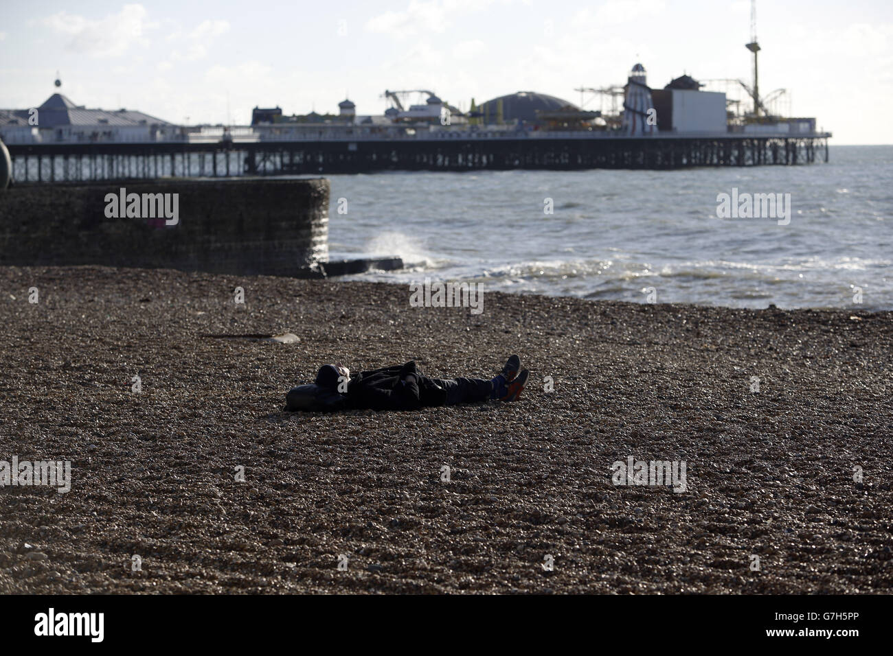 Un homme s'assoit sous le soleil d'hiver sur la plage de Brighton, dans le Sussex, tandis que le temps viviviviviriel et vivivivivivivivivivirira à travers la Grande-Bretagne cette semaine, suscitant la crainte de perturbations et de chaos dans les voyages. Banque D'Images