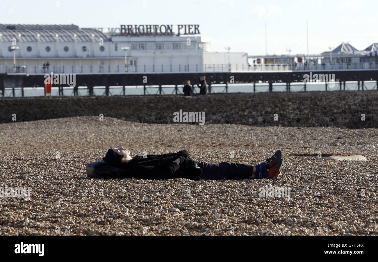 Un homme s'assoit sous le soleil d'hiver sur la plage de Brighton, dans le Sussex, tandis que le temps viviviviviriel et vivivivivivivivivivirira à travers la Grande-Bretagne cette semaine, suscitant la crainte de perturbations et de chaos dans les voyages. Banque D'Images