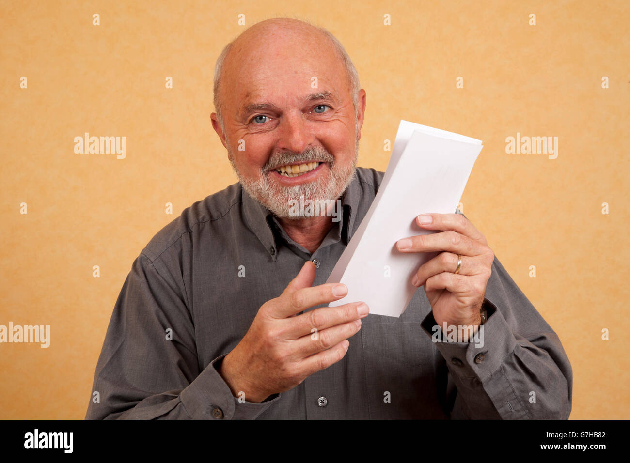 Un homme âgé, 59 ans, tenant une lettre, le projet de loi, à rire, heureux Banque D'Images