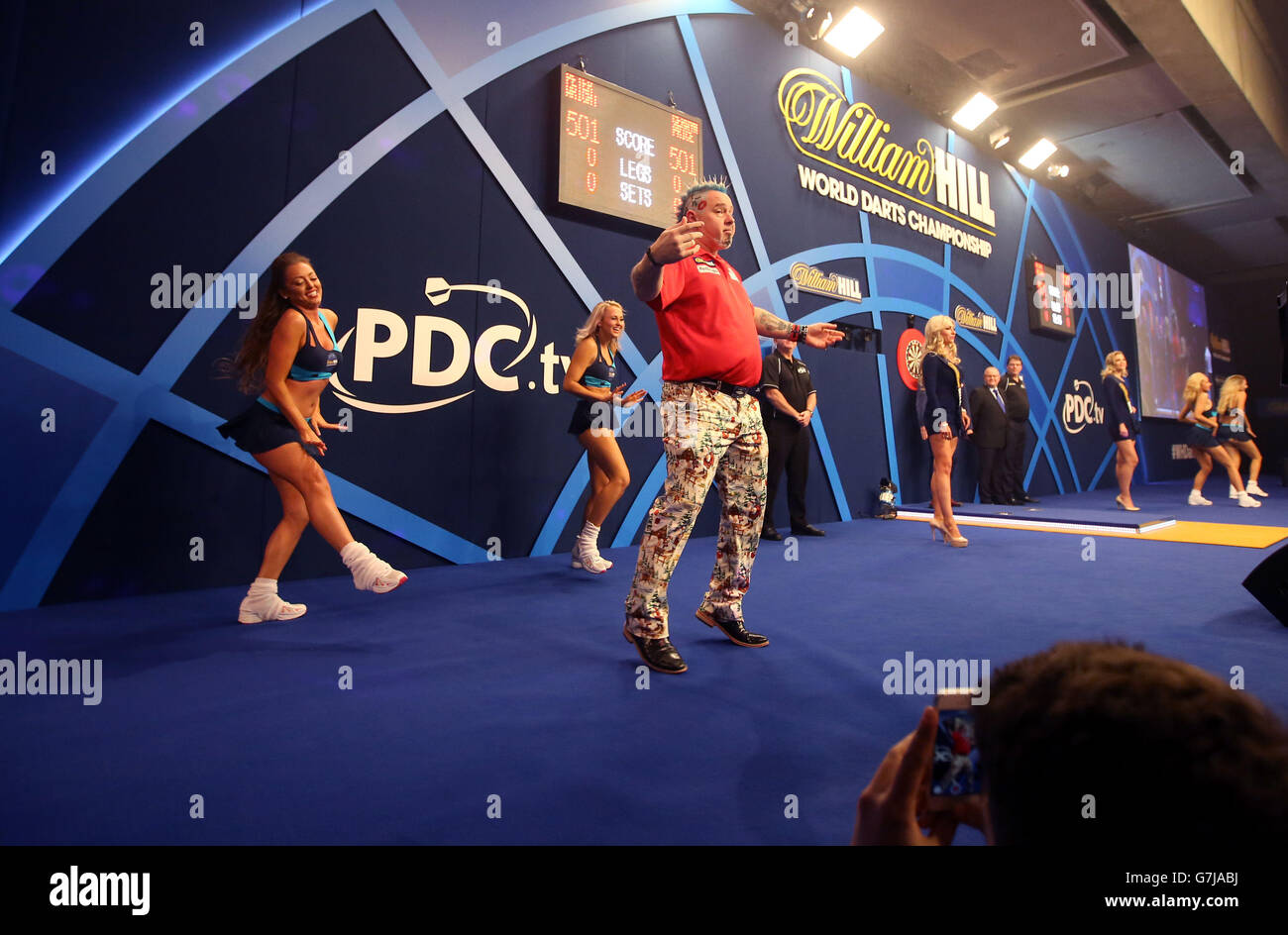 Peter Wright danse pour la foule alors qu'il arrive sur scène pour son match contre Gerwyn Price au championnat du monde des fléchettes William Hill à Alexandra Palace, Londres. Banque D'Images