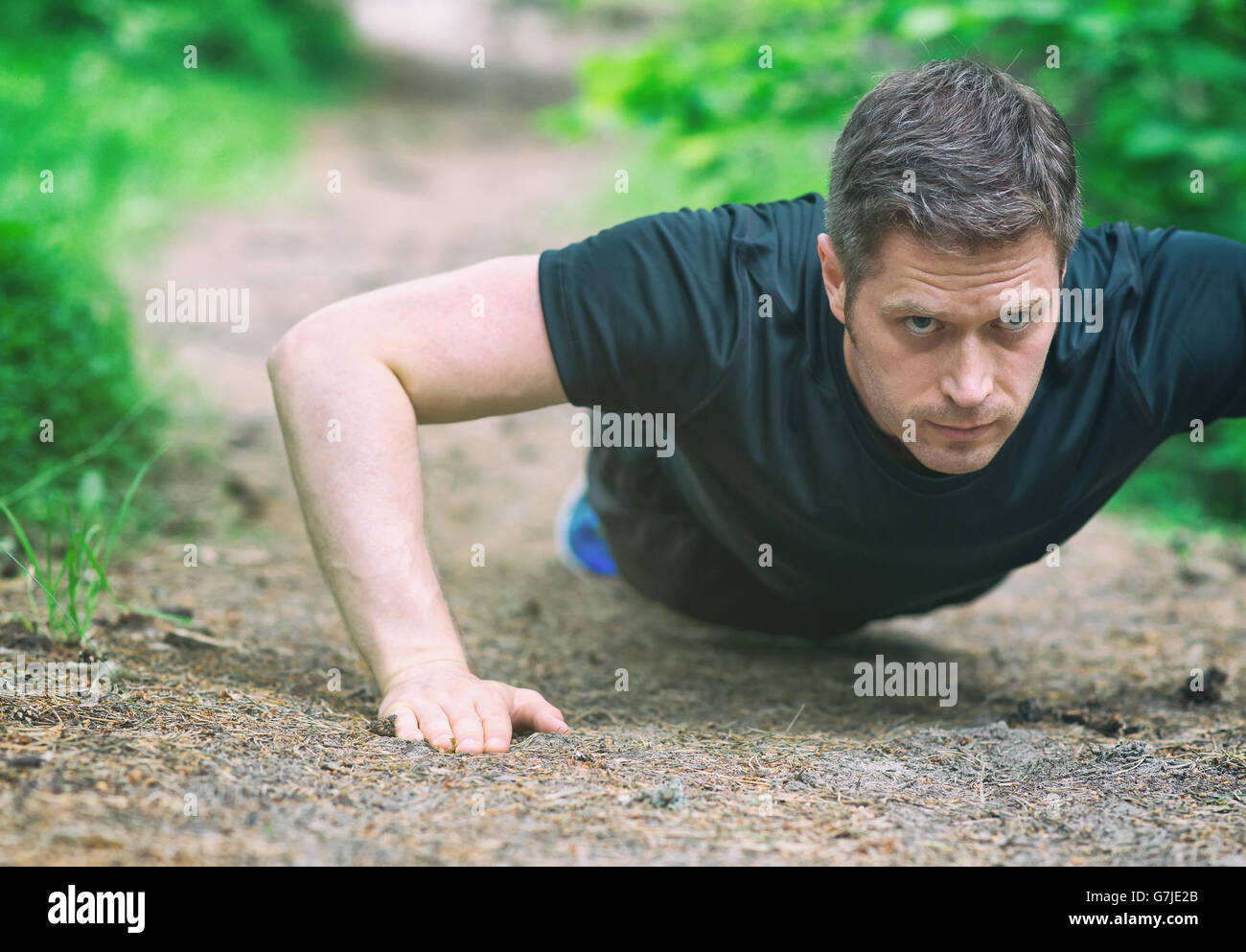 Bel homme faisant push-ups dans la forêt. Banque D'Images