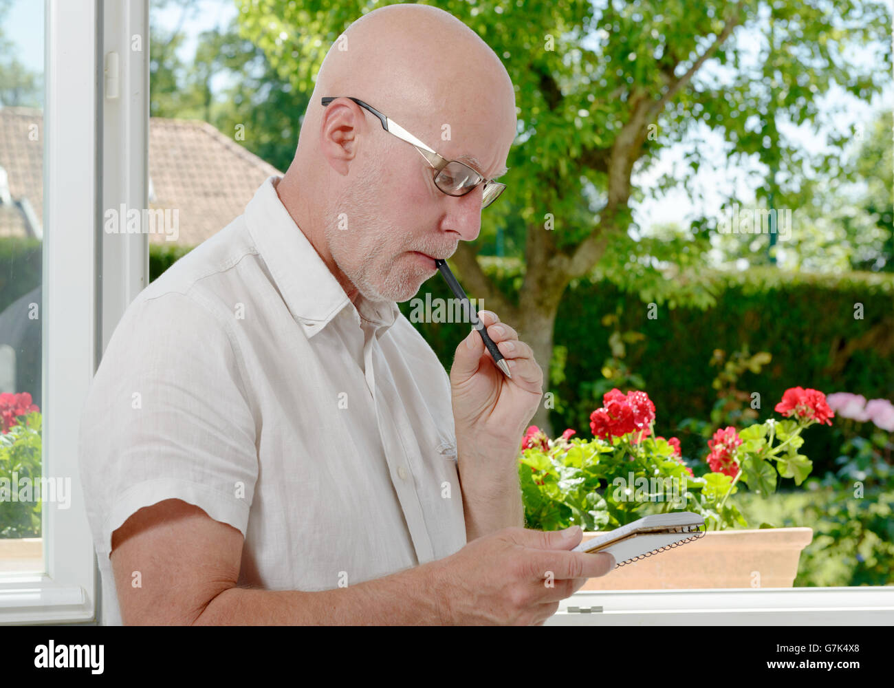 Un homme mûr près d'une fenêtre en prenant des notes Banque D'Images