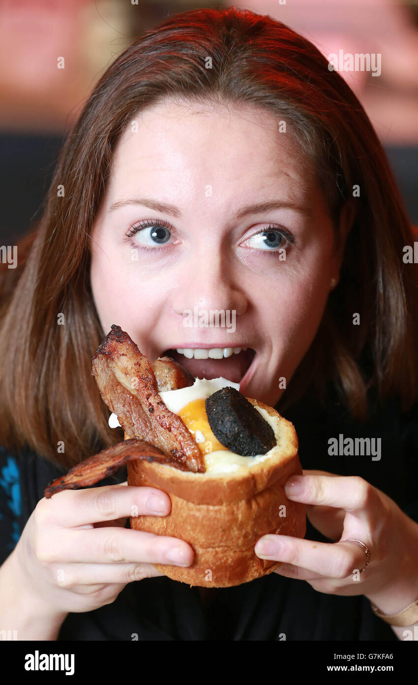 Lyndsay Anderson, de Londres, goûte le lapin anglais complet, alors que le chef de la télévision Phil Vickery présente le prix du meilleur petit déjeuner 2015 pour le petit déjeuner le plus innovant du Royaume-Uni à Atholl Milton PDG de Bunnychow, Pour le lapin anglais complet - un pain de brioche cuit individuellement qui est creux et rempli de saucisse, bacon maigre, tomates, champignons, haricots cuits épicés, pudding noir et recouvert d'un oeuf, à Bunnychow dans Wardour Street à Londres. Banque D'Images