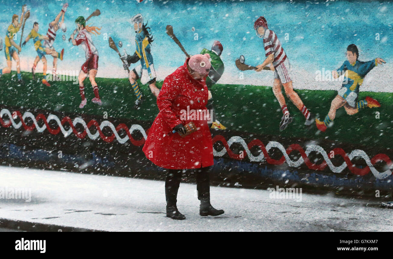 Une femme passe devant une murale dans la neige à l'ouest de Belfast alors qu'une alerte météo orange est annoncée en Irlande du Nord. Banque D'Images