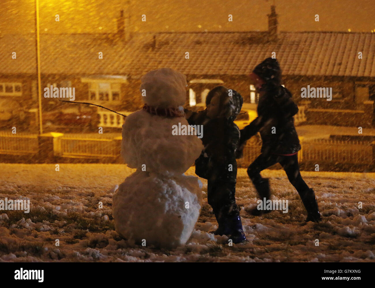 Des enfants construisent un bonhomme de neige dans l'ouest de Belfast, alors qu'une alerte météo orange est annoncée en Irlande du Nord. Banque D'Images