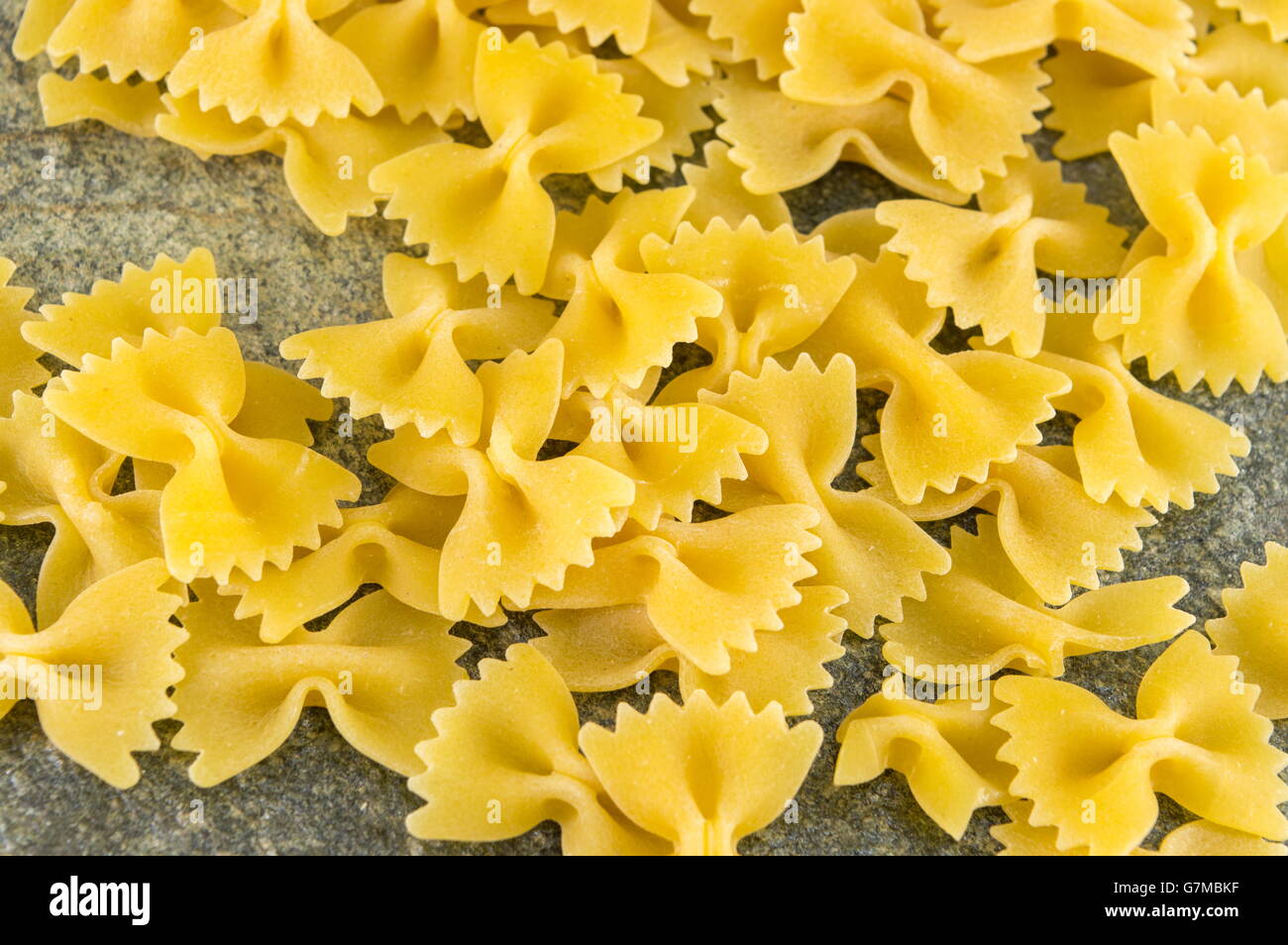 Pâtes farfalle papillon non cuits sur la table de cuisine en pierre Banque D'Images
