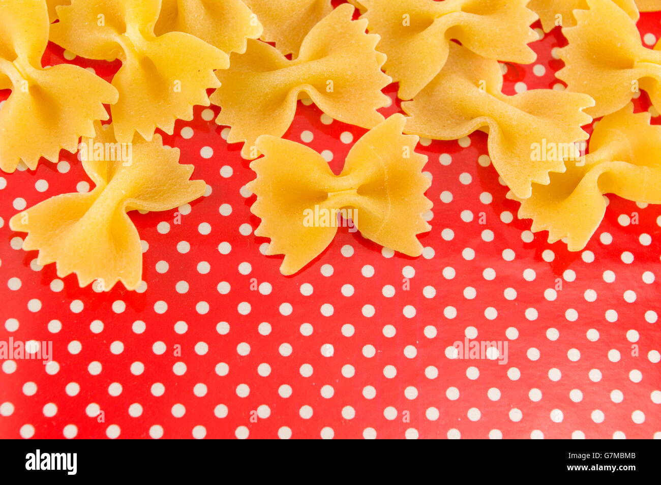Pâtes farfalle papillon non cuites sur red dotted background Banque D'Images