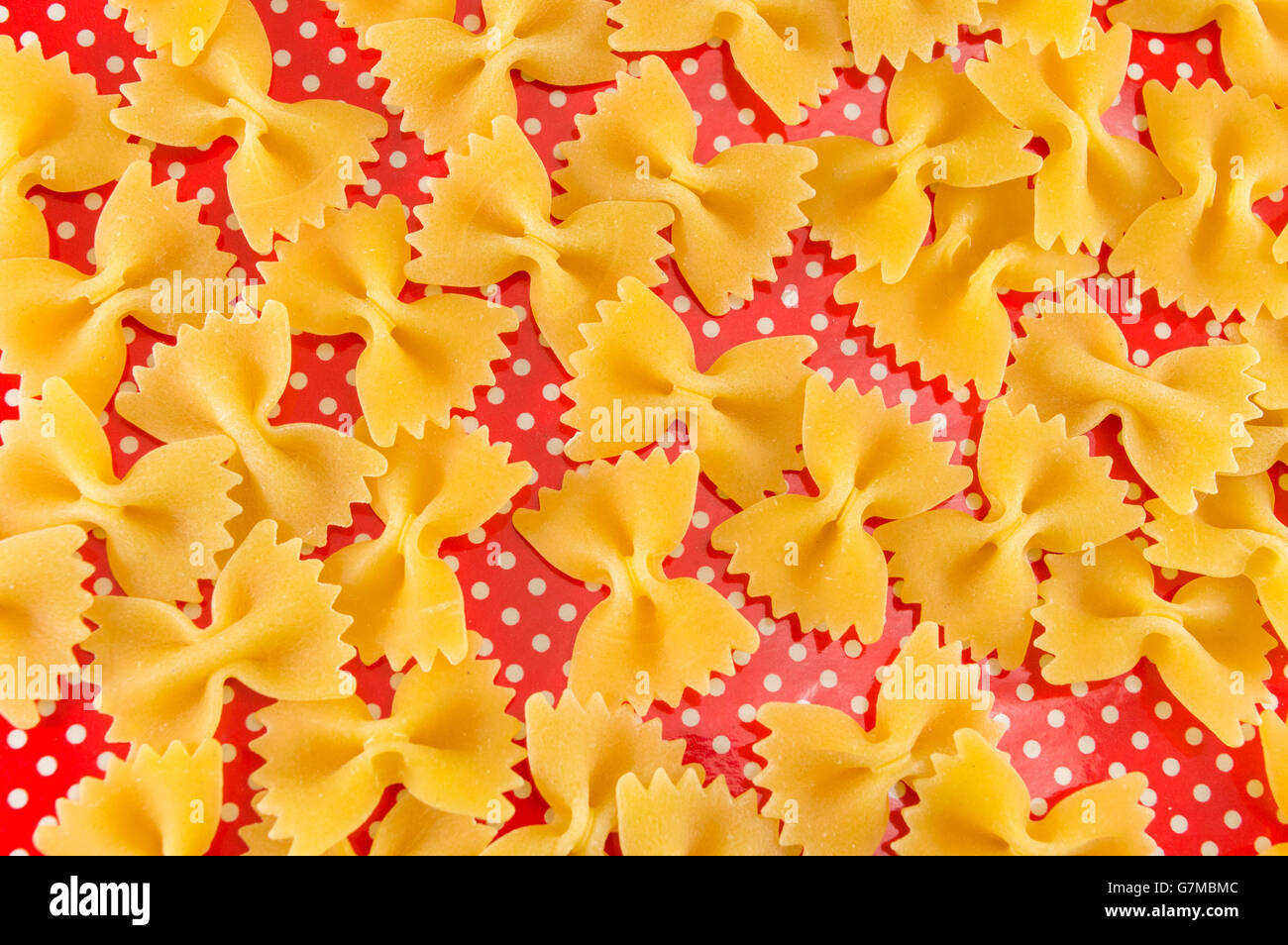 Pâtes farfalle papillon non cuites sur red dotted background Banque D'Images