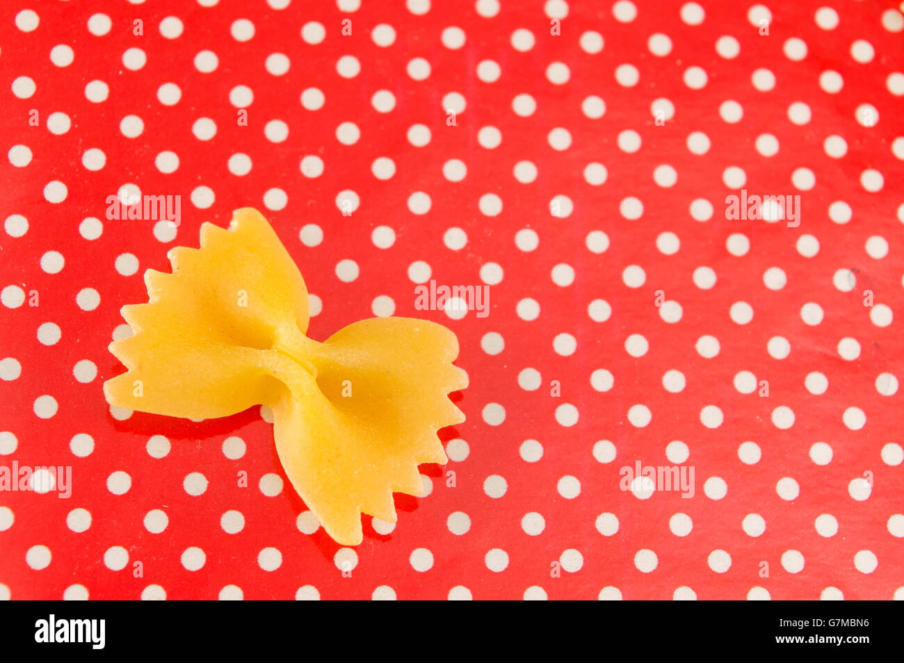 Pâtes farfalle papillon non cuites sur red dotted background Banque D'Images